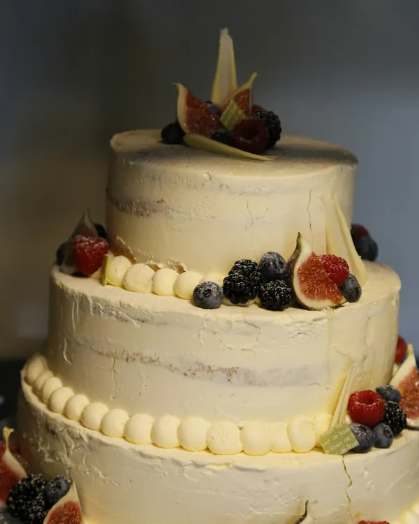 Un gâteau à trois étages, crème blanche, figues et mûres sur le dessus