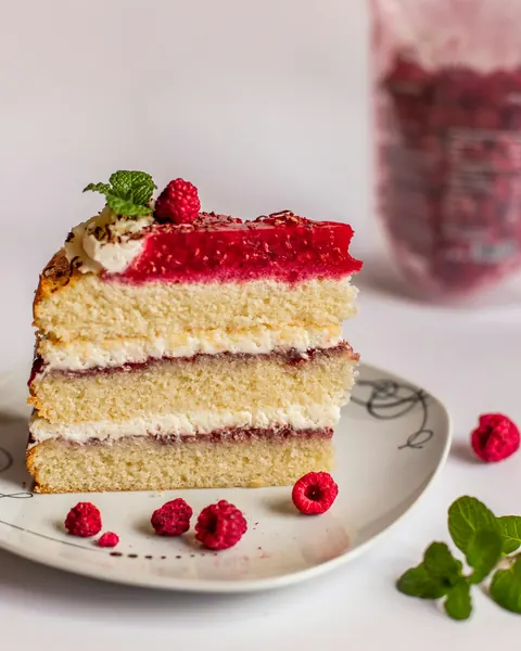 Un fraisier coupé : génoise, crème et framboises fraîches sur le dessus